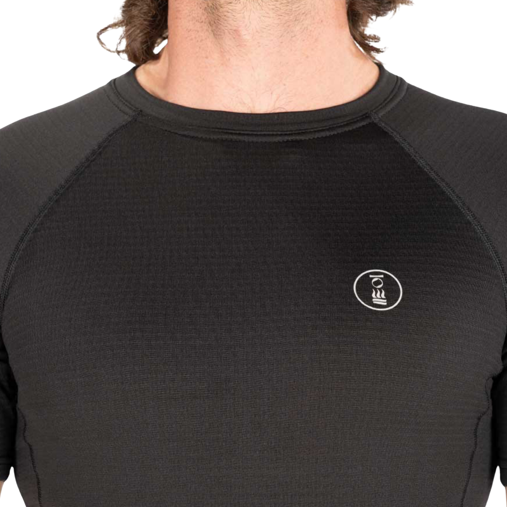 Close-up of a person wearing a black textured long-sleeve athletic top with raglan sleeves and a small white circular logo on the left chest, against a plain white background.