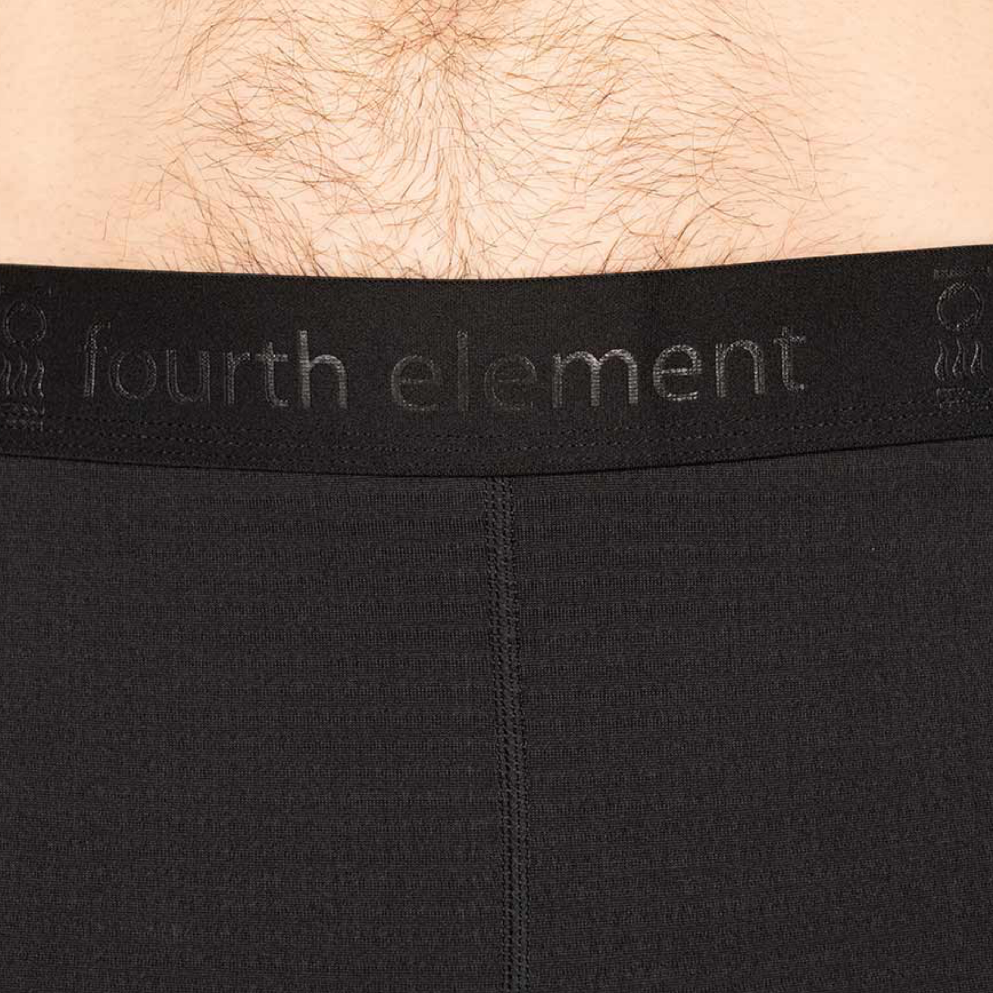 Close-up of a person wearing black underwear, showing the waistband with the embossed brand name 'fourth element' and a small size marking.