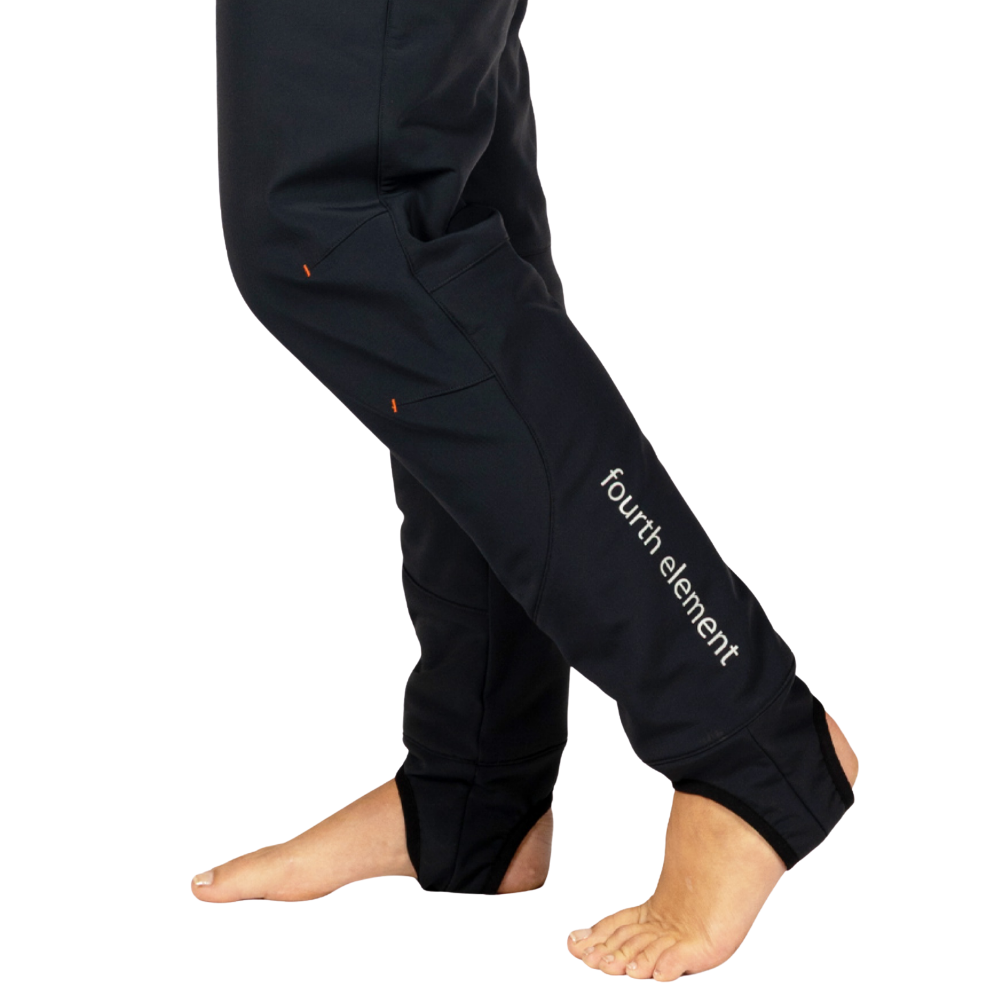 Black pants worn by a model, shown from the waist down with bare feet, featuring a white 'fourth element' logo on the lower left leg and small orange accent details.