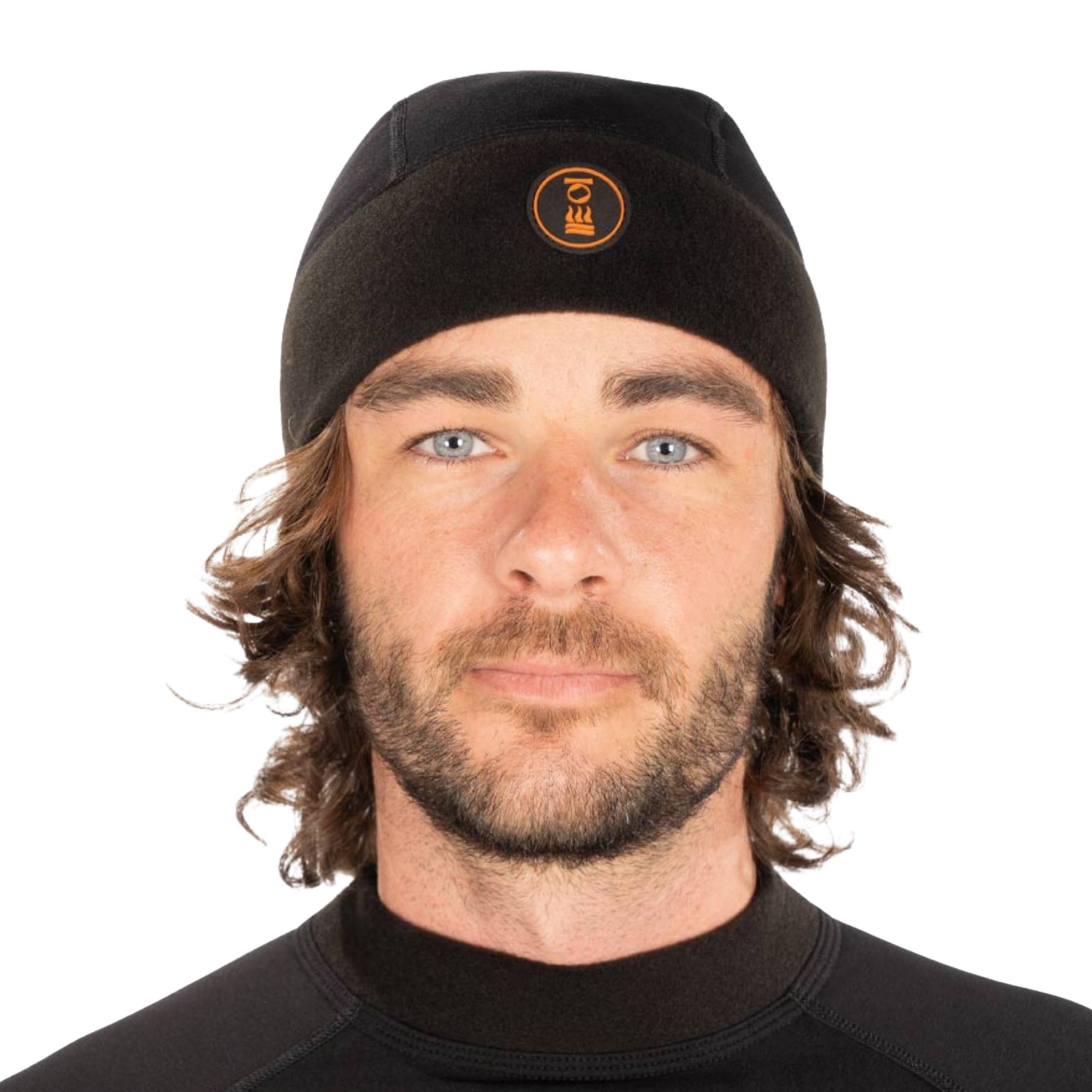 A man with long brown hair and a beard wearing a black knit beanie with a circular orange logo on the front, photographed against a plain white background.