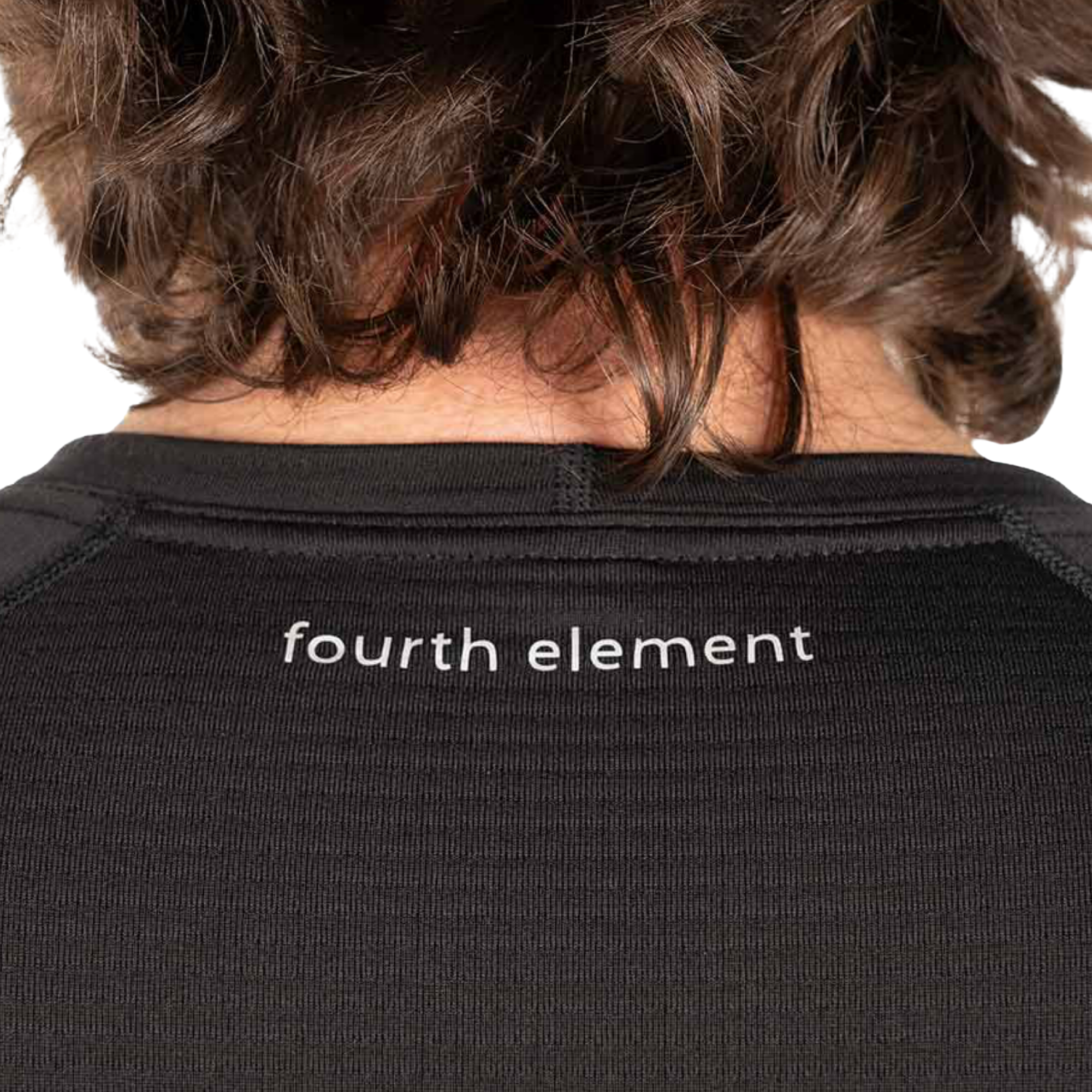 Close-up back view of a person wearing a black ribbed top with 'fourth element' printed in white across the upper back.
