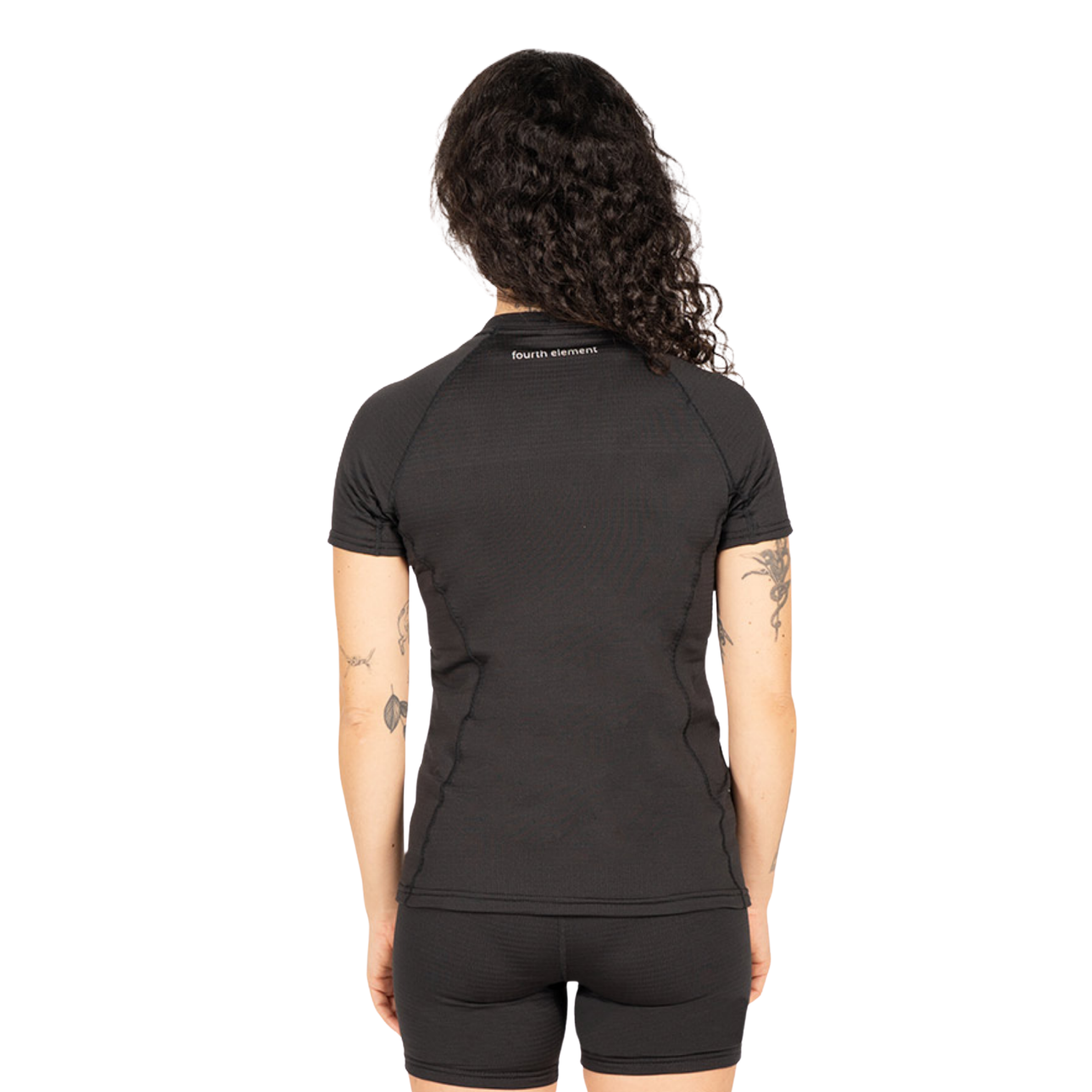 A woman viewed from the back wearing a fitted black short-sleeve athletic top and matching black shorts against a plain white background.